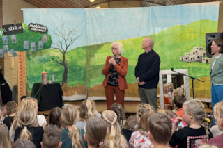 Kinderen luisteren naar presentatie op podium (1)